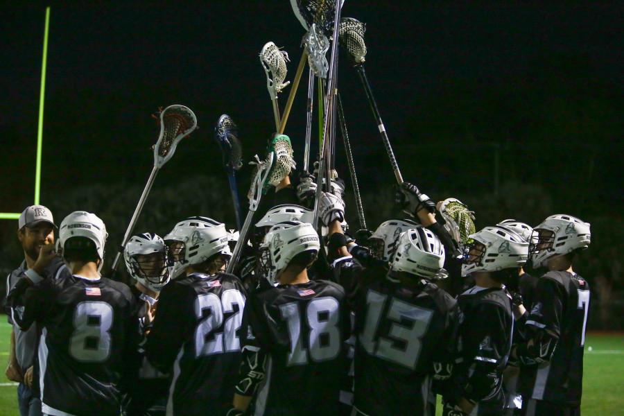 Lacrosse team gathers into a huddle at the start of a past game.