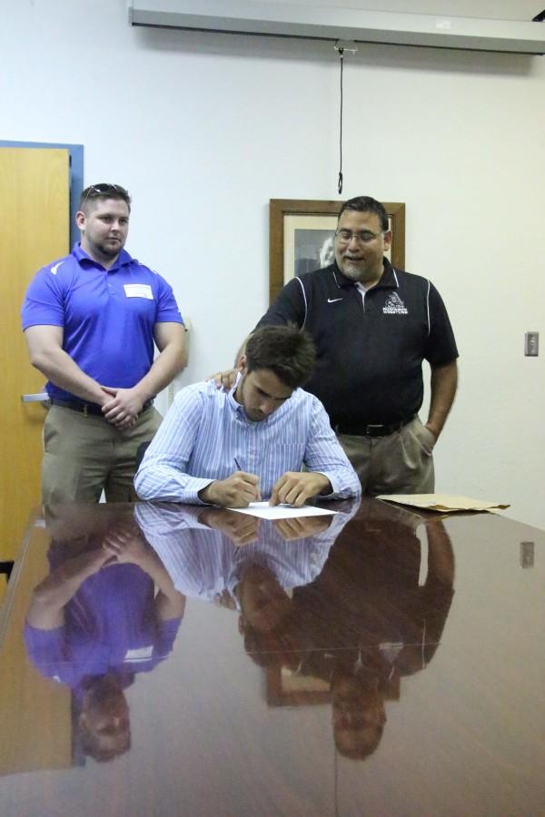 Senior Luis Peguero signs to Coker College on May 1st. His head coach, and long time family friend is seen behind him.