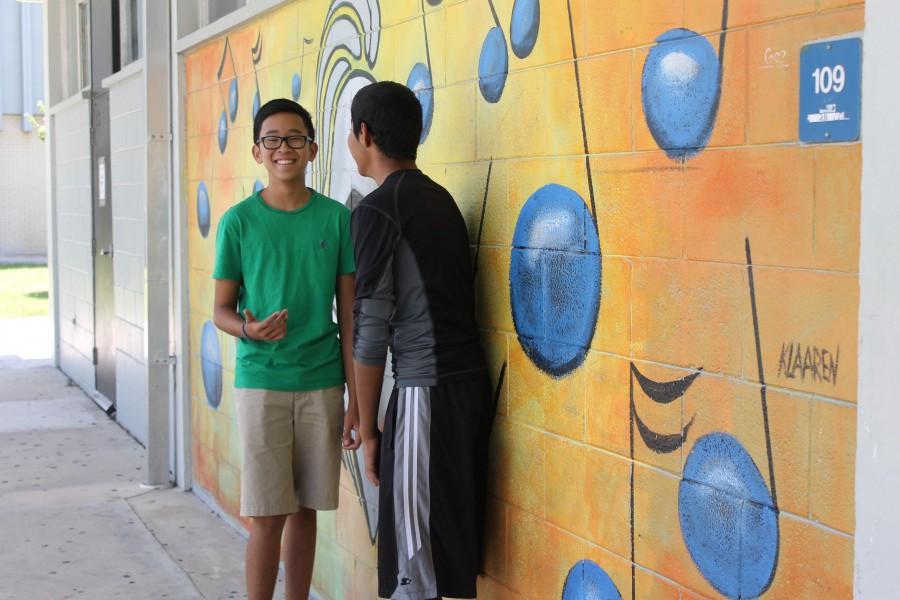Students converse by the mural  by the band room.