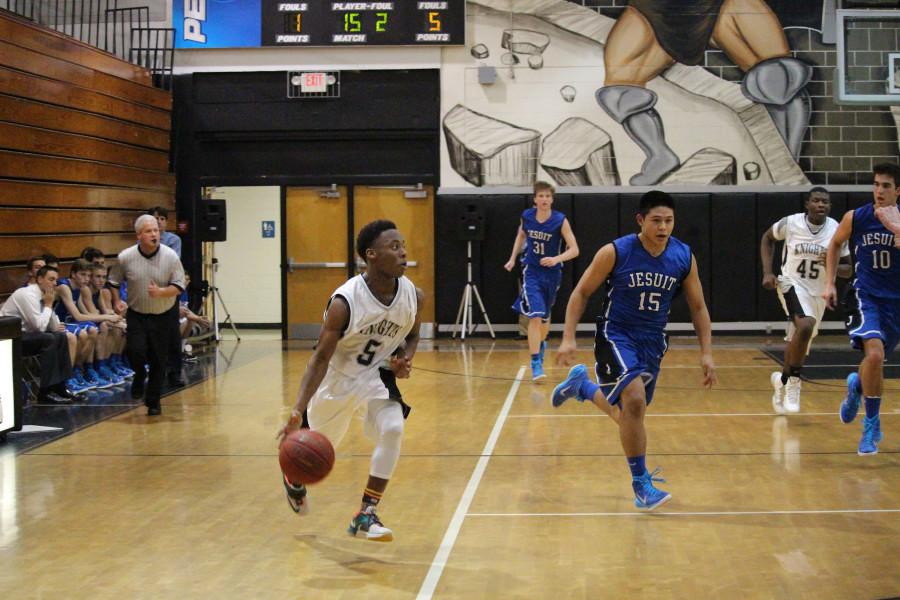 Guard Iyan Mitchell (15) dribbles the ball past Jesuits Rey Riveros (16).  Mitchell is also a member of the varsity football team.