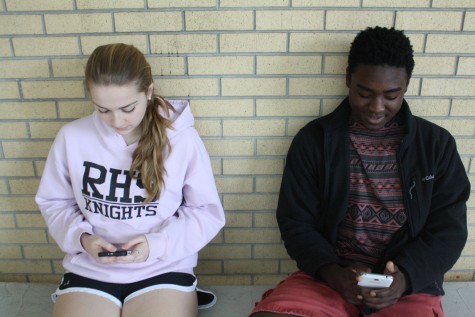 A common sight in many high schools, two students sitting together but too distracted by their phones to even look up. 