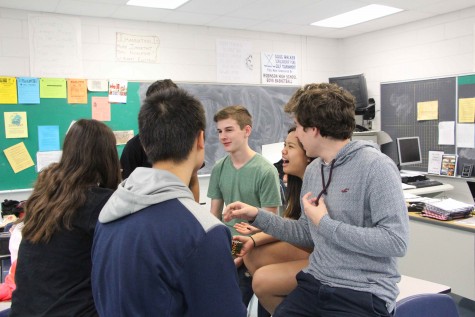 A group of sophomore students excitedly chit chat during lunch, exchanging drama. 