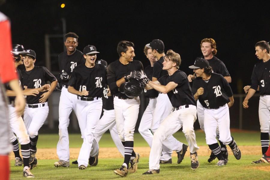 The team celebrates after Joey Scionti (17) delivered a game-winning sacrifice fly to score  Aaron Scott (17).