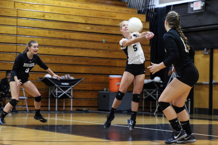 Captain and libero Emily Draper (17) digs as teammates Laura Hill (17) and Kristin Werdine (19) standby.