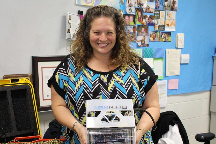 Here, IB Biology teacher Tiffany Oliver is featured with an underwater ROV robot she built during a STEM camp.