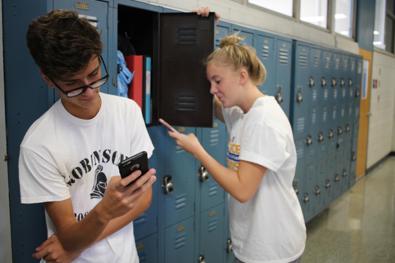 Abigail+Meyer+%2818%29+and+Andrew+McMillan+%2818%29+wait+in+the+halls+of+Robinson+on+their+cellphones.
