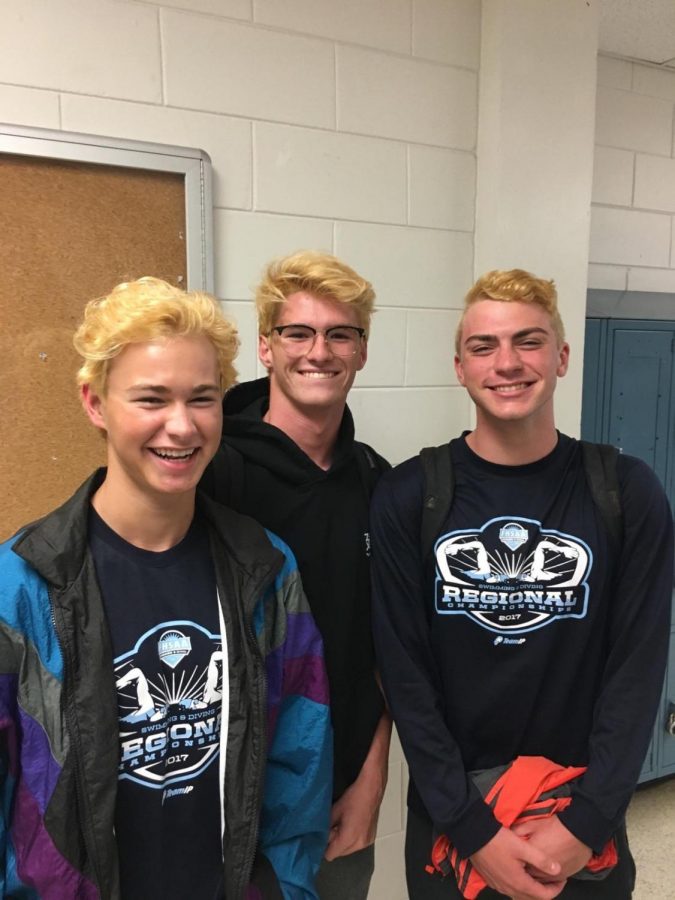 Daniel DeYoung (19), Max Smith (20) and Matthew Reinecke (18) all smile with their newly dyed blonde hair before they head to the state meet.