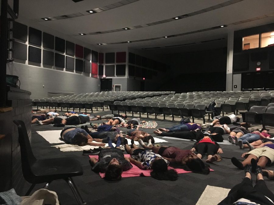 Students lie down around the auditorium and listen to the sounds of the speaker.
