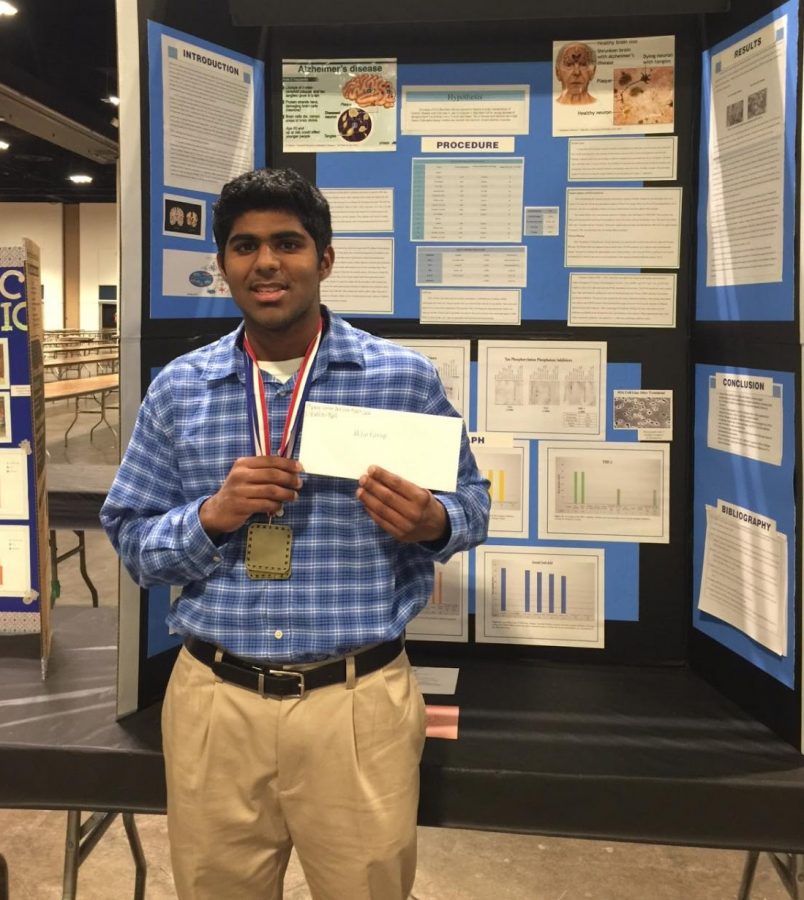 Milin Kurup (18) stands in front of his display of his science fair experiment. 