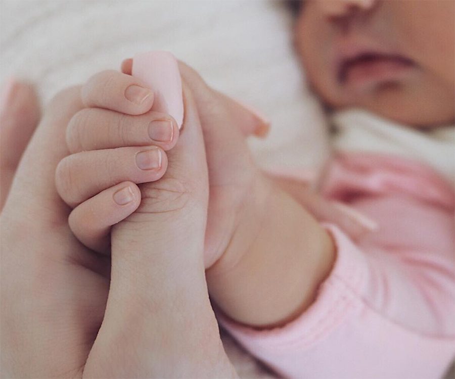 Stormi Webster, Kylie Jenners newborn child, holds on to her mothers thumb. 
