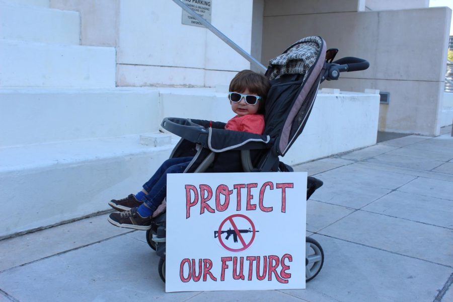 A mom places her sign in front of her childs stroller to add some emphasis on why she marches.