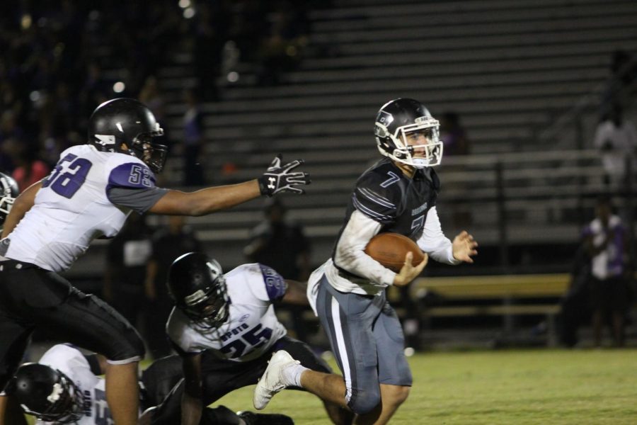 Quarterback Kobe Copple (19) escapes from pursuing defenders.