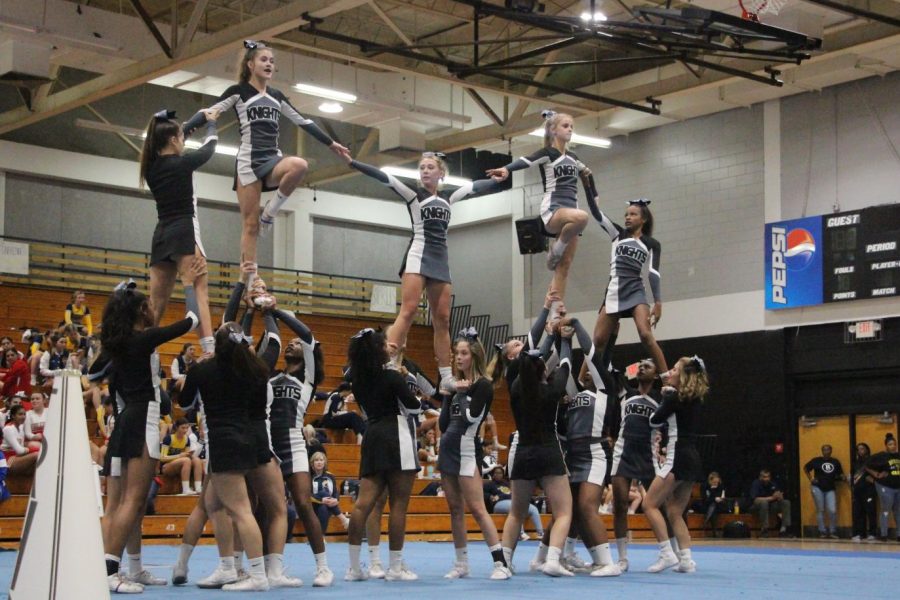 The+cheer+team+collaborates+to+form+a+full+pyramid+as+the+flyers+link+arms+in+the+air.