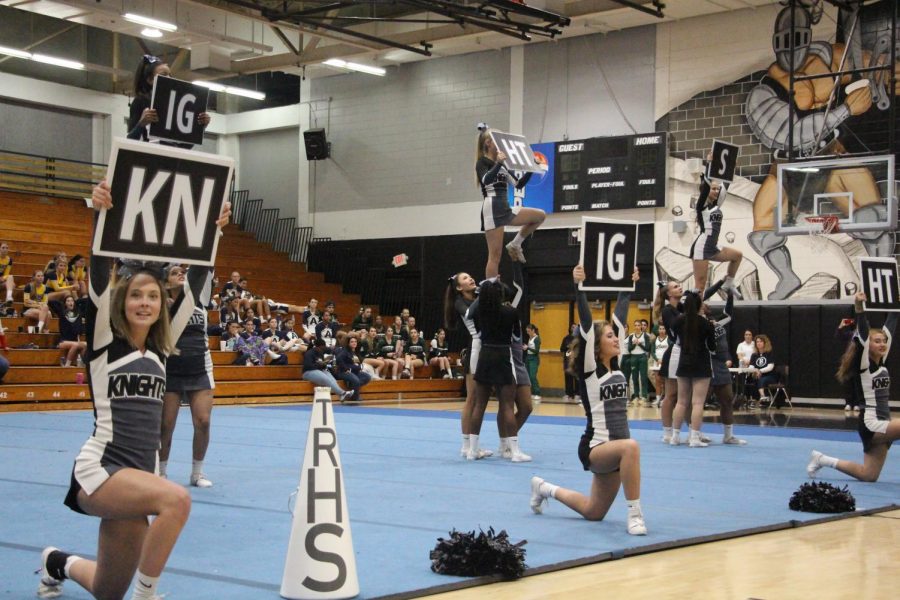 The cheer team holds signs, reading the word knights.