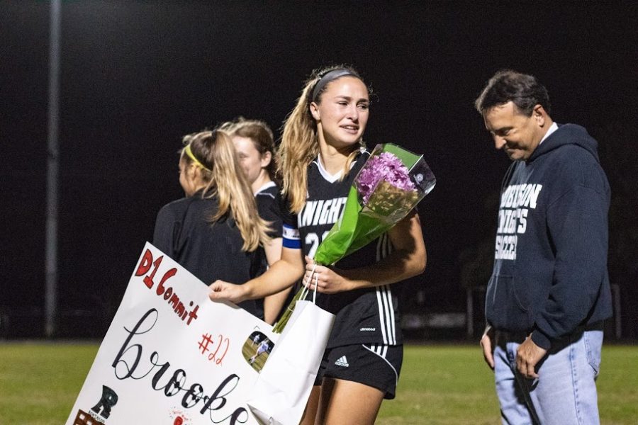 Head captain Brooke Volpi (20) walks the soccer field and is welcomed by her team.
