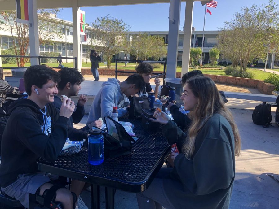 Owen Higgins (21) (far left) socializes with his friends during lunch after returning for the second quarter.