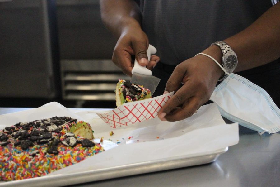 A judge gathers a slice of rainbow cake, decorated with sprinkles and Oreos. Judges were instructed to take samples of each cake and rank them on a set of criteria.