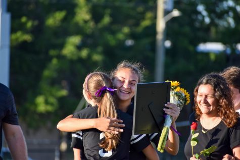 A teary-eyed Bella Dolce (21) pulls Jaylen Stasio (22) into a hug after receiving a bouquet of flowers, a framed photo and other gifts commemorating her time on the team. 