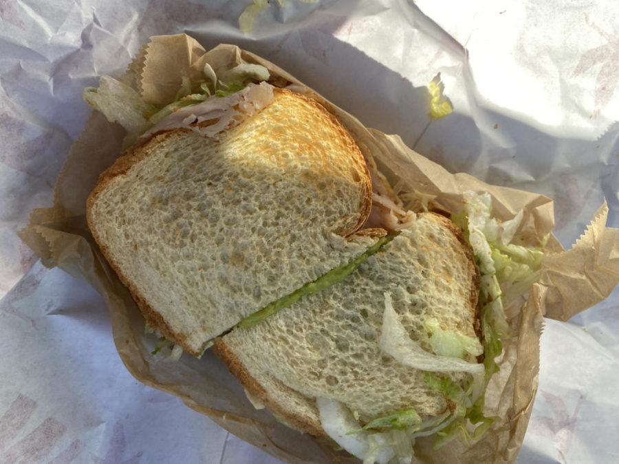 A Wawa turkey sandwich on white bread with lettuce and avocado.