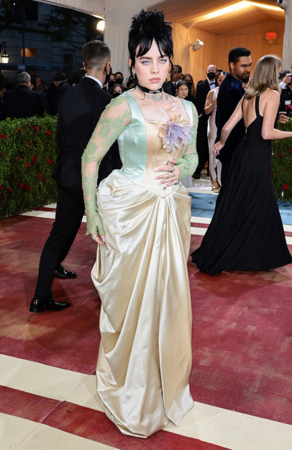 Billie Eilish attends The 2022 Met Gala with the theme Gilded Glamour. The pastel tones of her dress contradicts her bold makeup and accessories. 