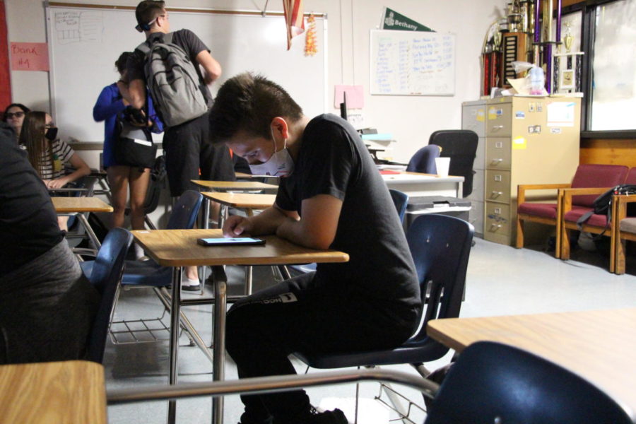 Oscar Penagos (22) plays on his phone in the moments before his teacher enters the classroom.