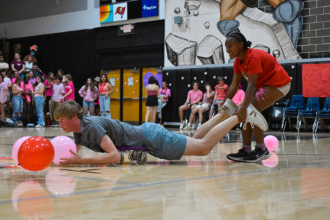 Adriana Williams (23) (right) drags Hunter Smith (23) back to their corner with their newly acquired balloons in the Hungry Hungry Hippos game. 