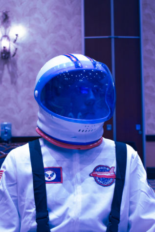 A boy in an astronaut suit gazing around the ballroom.