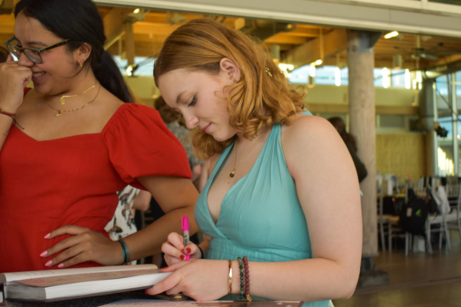 Julia Cardillo (23) signs her classmates yearbook at the IB Senior Banquet. The event took place at the Tampa River Center at Julian B Lane Park on Monday, May 22. 