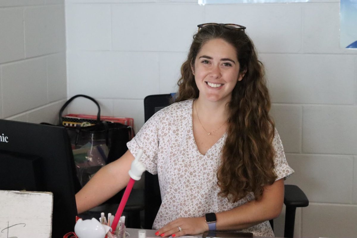 Espejo smiles at the camera while putting in grades in her computer. 