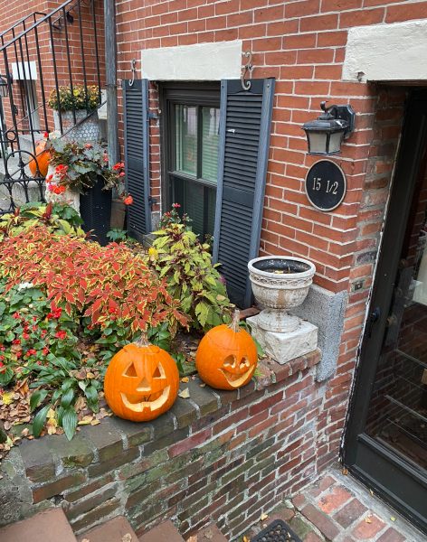 Two jack-o-lanterns in front of a house in a neighborhood in Boston. 