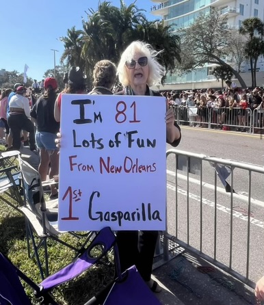 Lady holds up sign saying it is her first year at Gasparilla. 