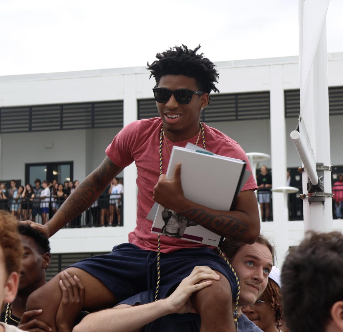 Darius Walsh (24) riding on his friends shoulders clutching his yearbook during the senior clap-out.  