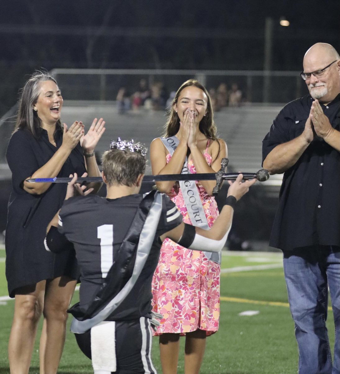 Homecoming King Xander Logan (‘25) presents newly announced Queen, Lauren Launikitis (‘25) with the sword. 