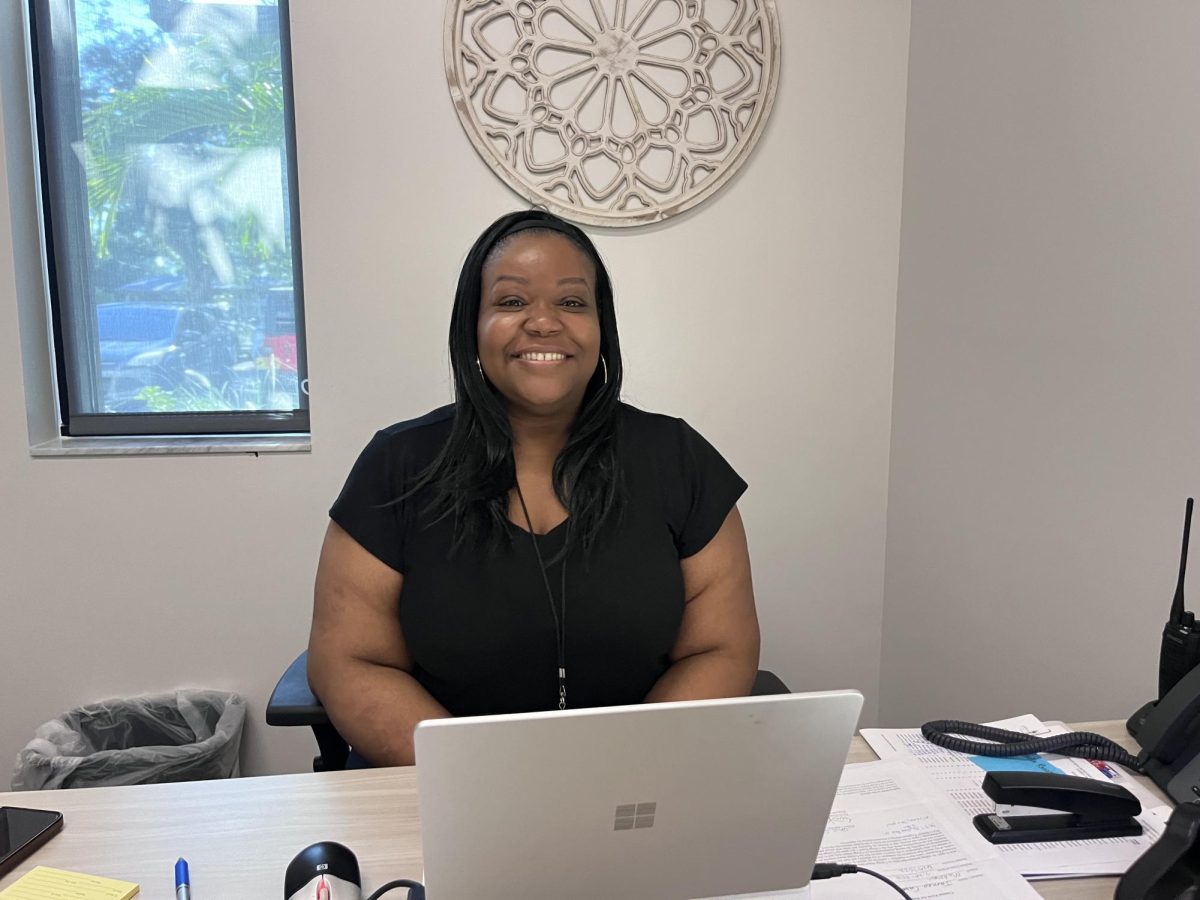 Sherly Gervais gives a bright smile while sitting in her new office at her desk. 