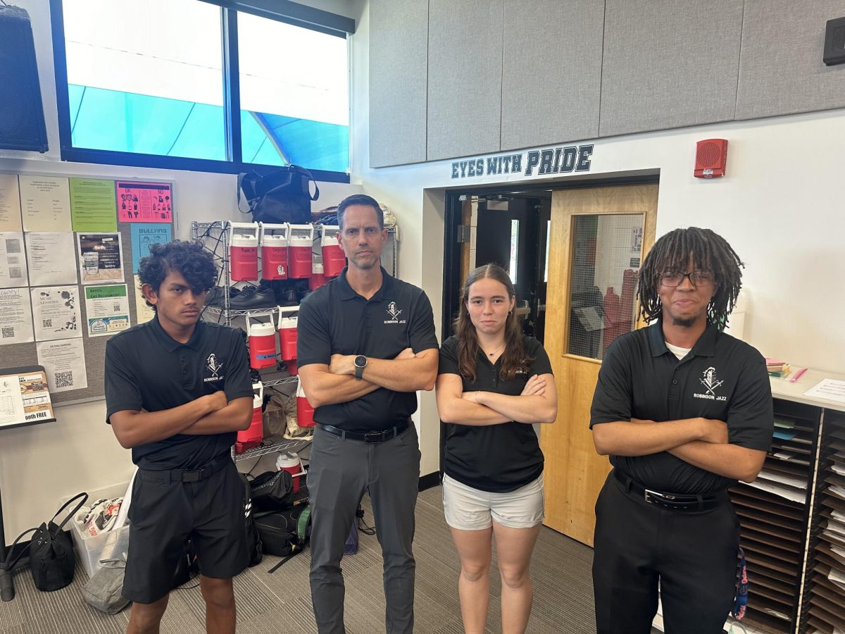 Band students Catie Powell ('25), Jonaz Awad ('25) and James Andrews ('26) pose as Mr. Revvett, the band director, on the second day of Homecoming spirit week. They even sported his signature glare, as if watching them attempt to march the fourth movement of this year's show. "He was like " I haven't even worn that shirt in months, this is crazy," Powell said. 