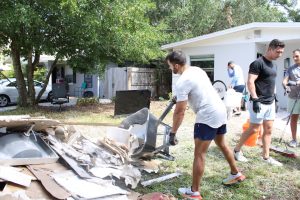 A local adds to the pile of rubbish in front of his home while cleaning out flood-damaged debris post Helene.