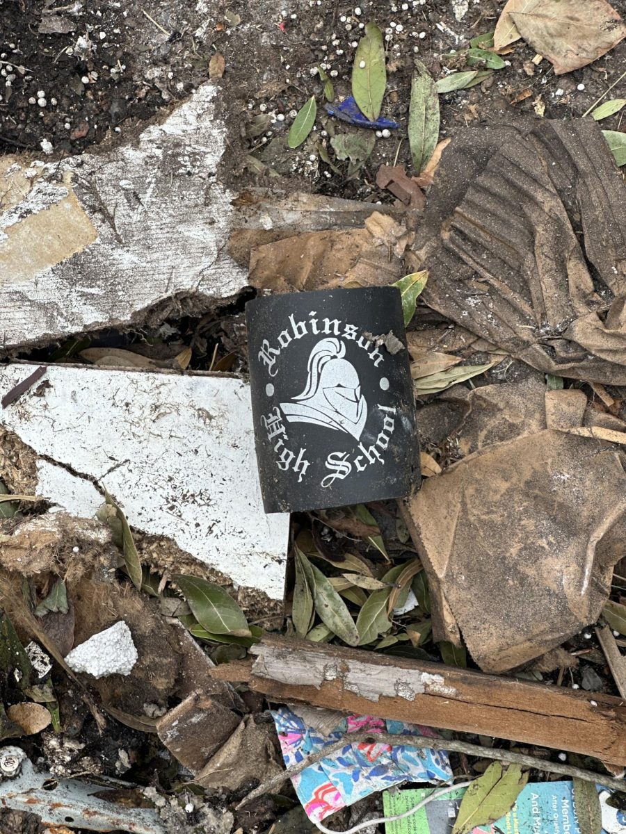 A Robinson High School koozie rests in a pile of trash and yard debris