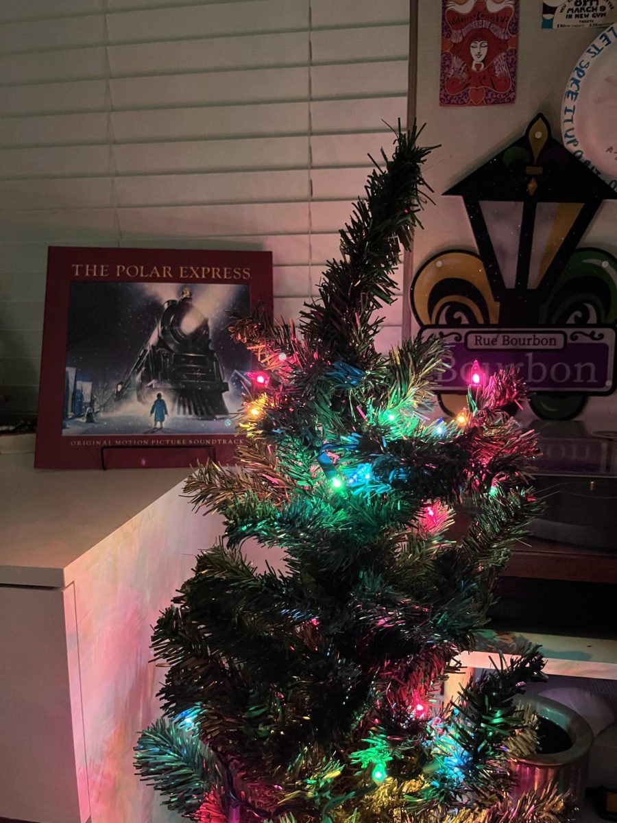 A mini-Christmas tree lit by colorful lights accompanied by the vinyl record of The Polar Express. 