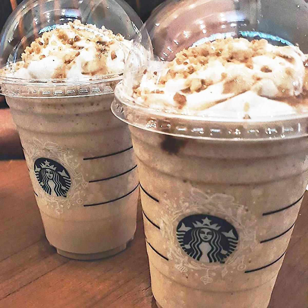 Two Christmas cookie frappes from Starbucks topped with whipped cream and cookie crumble on top. 