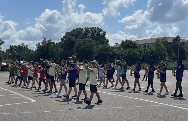 The marching band practices their show in the driver's ed parking lot.