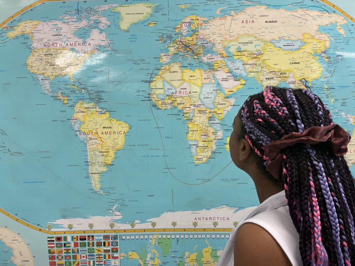 A student, Chloe Linjewile (28'), looking at a map of the world in class. 